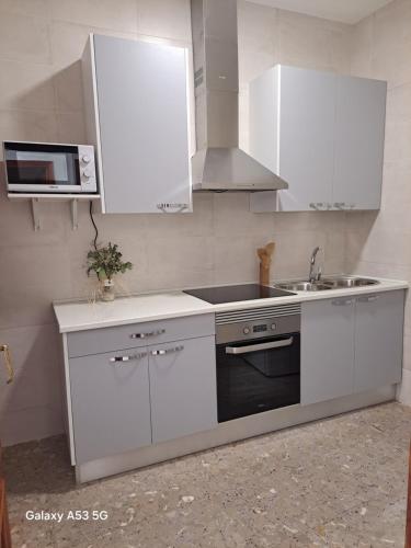 a kitchen with white cabinets and a sink and a microwave at La casilla in Herencia