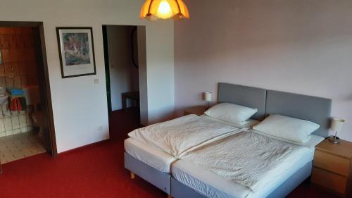 a bedroom with a large bed with white sheets at Waldpension Rabeneck in Waischenfeld
