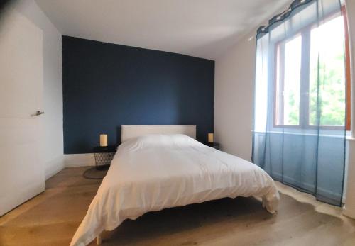 une chambre avec un grand lit et un mur bleu dans l'établissement Le Valentin Charmant 2 pièces, à Belfort