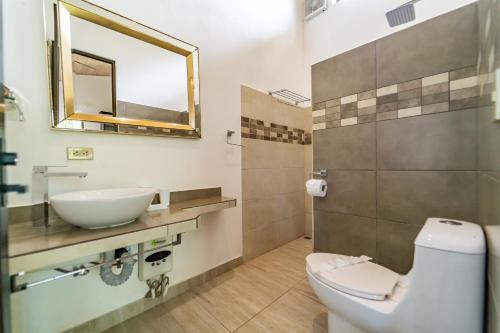 a bathroom with a sink and a toilet and a mirror at Las Perlitas Rentals Playa Samara in Sámara