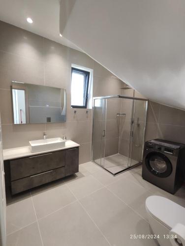 a bathroom with a shower and a sink and a washing machine at Arillas Villas dinos in Arillas