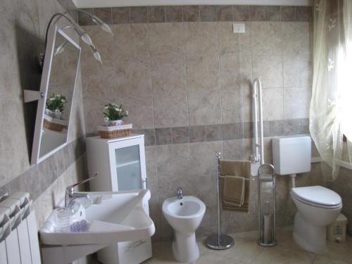 een badkamer met een wastafel, een toilet en een spiegel bij Corte Dante in Taglio di Po