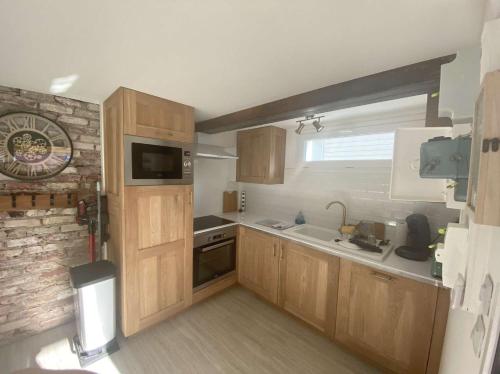 Elle comprend une petite cuisine avec des placards en bois et un mur en briques. dans l'établissement green, à Fort-Mahon-Plage
