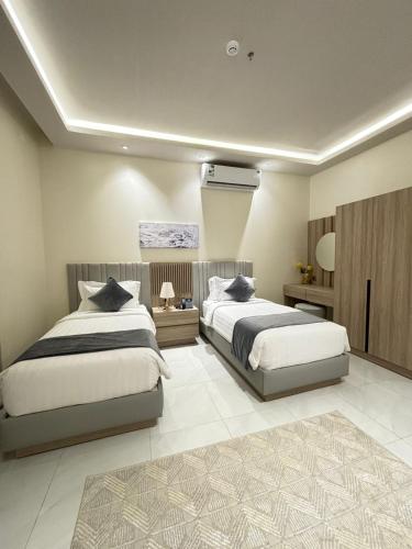 a bedroom with two beds and a air conditioner at رنز بالاس للشقق الفندقية in Dammam