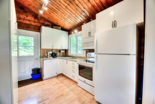 a kitchen with white appliances and a wooden ceiling at Domaine Chalets des pins in Rawdon