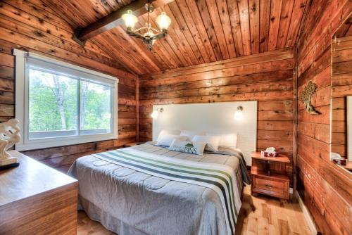 a bedroom with a bed in a wooden cabin at Domaine Chalets des pins in Rawdon