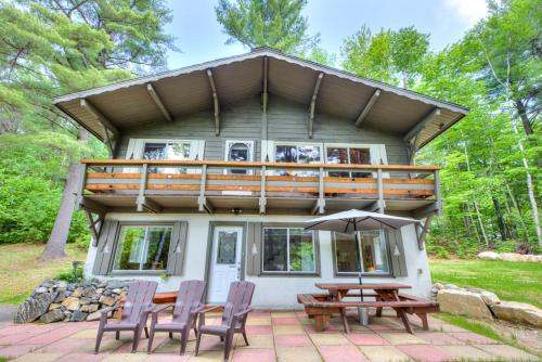a house with a deck and a picnic table and chairs at Domaine Chalets des pins in Rawdon