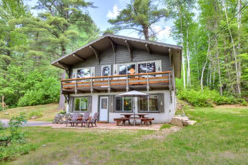 a cabin in the woods with a deck and picnic tables at Domaine Chalets des pins in Rawdon