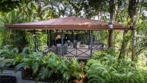 a gazebo with chairs and tables in a garden at Hotel Boutique Casa Del Rio in Fortuna