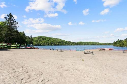 a beach with benches and boats on the water at Chalet Mon Repos - Lac Sarrazin avec embarcations in Sainte-Lucie-de-Doncaster