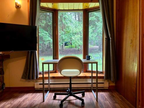 a desk with a chair in front of a window at Chalet Mon Repos - Lac Sarrazin avec embarcations in Sainte-Lucie-de-Doncaster