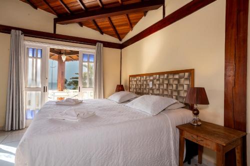 a bedroom with a large white bed and a window at Pousada Bonns Ventos in Ilhabela
