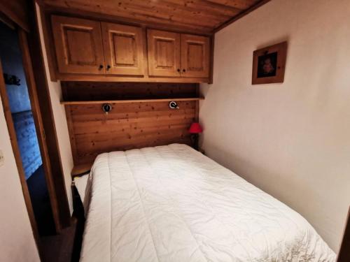 - un petit lit dans une petite chambre avec des placards en bois dans l'établissement Résidence Proveres - PROVERES 41 MAE-4001, à Les Allues
