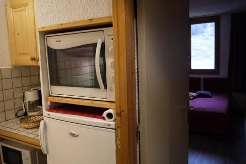 un micro-ondes au-dessus d'un réfrigérateur dans une cuisine dans l'établissement Résidence Candide - CANDIDE C12 MAE-4061, à Les Allues