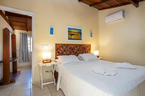 a bedroom with a large white bed and two lamps at Pousada Bonns Ventos in Ilhabela