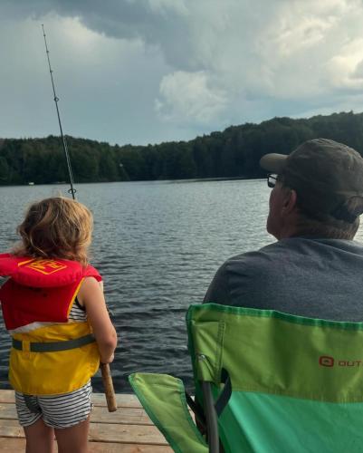 a man and a little girl fishing on a dock at Domaine Chalets des pins in Rawdon
