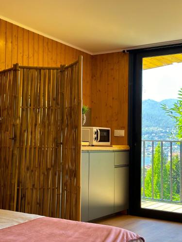 a kitchen with a microwave on a counter next to a window at Bungalow Bétula - Pichoses Camping - Gerês in Rio Caldo