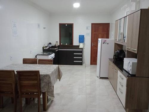 a kitchen with a table and a white refrigerator at Casa em Piuma proximo a praia in Piúma