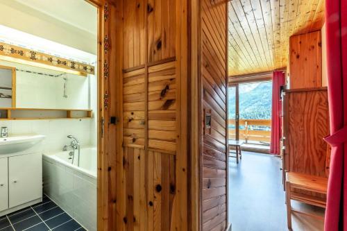 La salle de bains est pourvue d'un mur en bois, d'une baignoire et d'un lavabo. dans l'établissement Résidence Plattieres - PLATTIERES 4 MAE-4241, à Les Allues