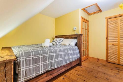 a bedroom with a bed with yellow walls and wooden floors at Rustic nature retreat with Hot Tub in Saint Adolphe D'Howard