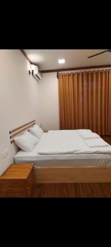 a bedroom with a large bed and a curtain at Oibeach in Maamigili