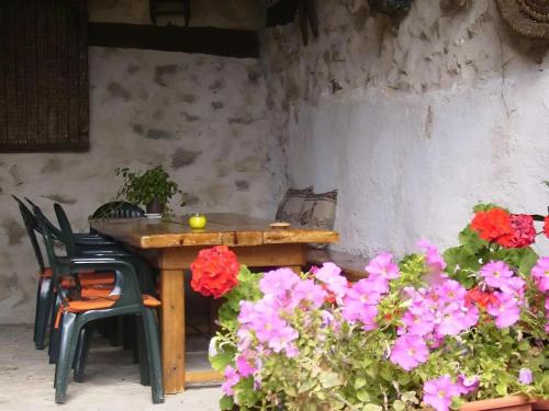 a wooden table and chairs and some flowers at Casa Rural El Fresno del Abuelo in La Cuesta