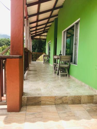 a green building with tables and chairs on a porch at KETHALYA TAYRONA Hostal in El Zaino