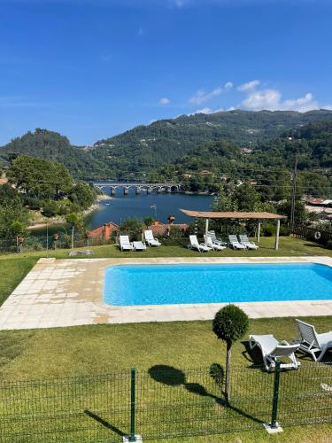 a swimming pool with chairs and a view of a lake at Bungalow Bétula - Pichoses Camping - Gerês in Rio Caldo