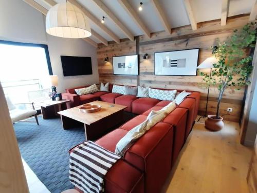 un salon avec un canapé rouge et une table dans l'établissement Chalets De La Grande Ourse - Sublime Chalet 16 personnes avec sauna & Jacuzzi ! MAE-8951, à La Plagne Tarentaise