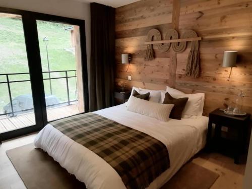 ein Schlafzimmer mit einem Bett und einem großen Fenster in der Unterkunft Chalets De La Grande Ourse - Sublime Chalet 16 personnes avec sauna & Jacuzzi ! MAE-8951 in La Plagne Tarentaise