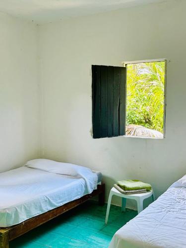 a bedroom with two twin beds and a window at Casa de las brujas hostal in Zipolite