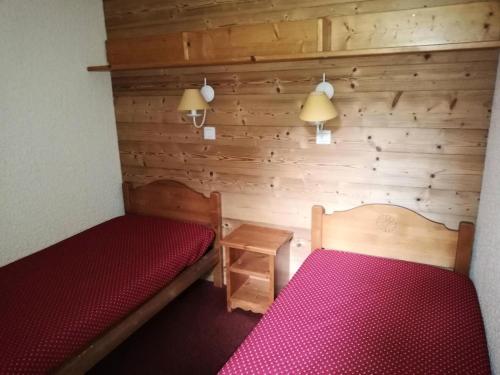 - une chambre avec 2 lits et un mur en bois dans l'établissement Résidence Lauzes G - LAUZES 24 MAE-6031, à Valmorel