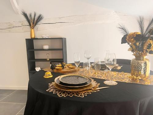 une table avec un tissu de table noir, des verres et un vase dans l'établissement Love Room Luxure 50 Nuances, à Jonzac