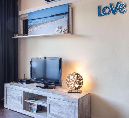 una TV a schermo piatto seduta sopra un centro di intrattenimento in legno di Vista Pujols playa ubicación magnífica a Es Pujols