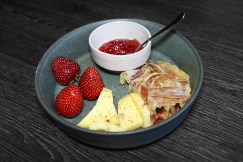 a plate of food with strawberries and a bowl of sauce at Smaken av Ryfylke Event AS overnatting, Bygningen drives ikke som hotell in Hjelmeland