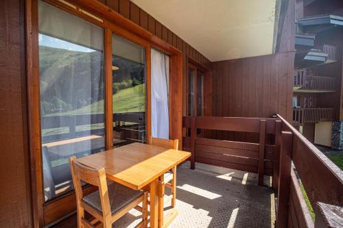 une table et des chaises en bois sur un balcon dans l'établissement Résidence Cristallin G - CRISTALLIN 13 MAE-6251, à Valmorel