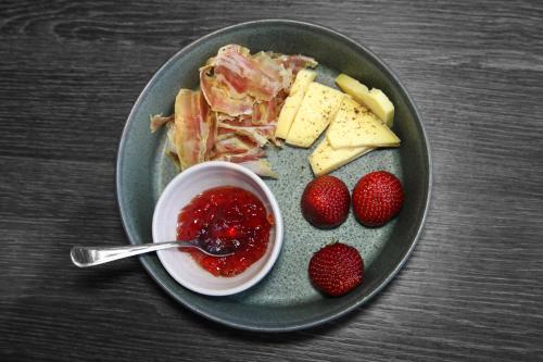 a plate of food with cheese and strawberries on a table at Sleeping barrel lodge Smaken av Ryfylke Event AS, drives ikke som hotell in Hjelmeland