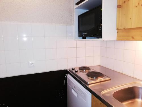 Il comprend une petite cuisine équipée d'une cuisinière et d'un évier. dans l'établissement Résidence Prariond G - PRARIOND 18 MAE-6501, à Valmorel