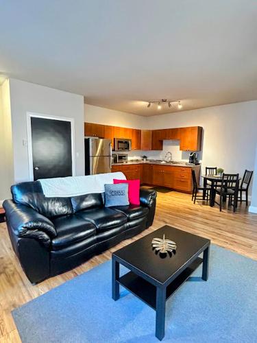 a living room with a black leather couch and a table at Cribs on the Hill in Picton