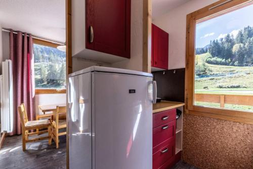 une cuisine avec un réfrigérateur, une table et une fenêtre dans l'établissement Résidence Roche Combe G - ROCHE COMBE 15 MAE-6621, à Valmorel