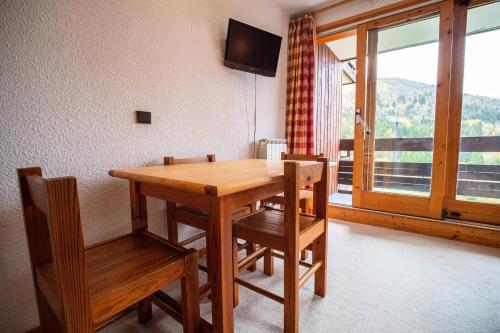 - une table et des chaises en bois dans une chambre avec fenêtre dans l'établissement Résidence Cristallin G - CRISTALLIN 12 MAE-6651, à Valmorel