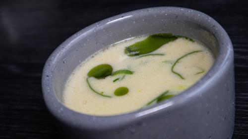 a white bowl of soup with green vegetables in it at Sleeping barrel lodge Smaken av Ryfylke Event AS, drives ikke som hotell in Hjelmeland