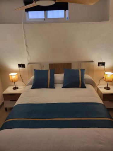a bedroom with a bed with blue pillows and two lamps at Apartamento La Avenida in Lanjarón