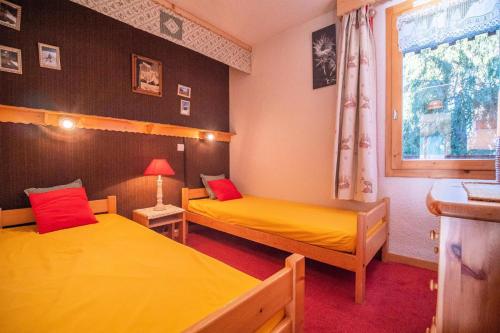 - 2 lits dans une chambre avec des draps jaunes et des oreillers rouges dans l'établissement Résidence Cheval Noir G - CHEVAL NOIR 23 MAE-6791, à Valmorel