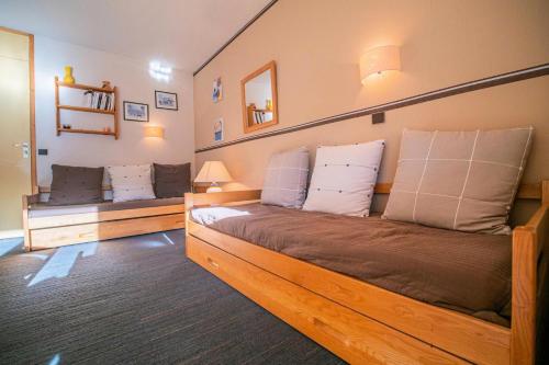 - une chambre avec un grand lit en bois et des oreillers blancs dans l'établissement Résidence Cheval Noir G - CHEVAL NOIR 24 MAE-6821, à Valmorel