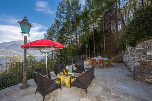 patio ze stołem, krzesłami i parasolem w obiekcie Villa Aquila w mieście Pianello Del Lario
