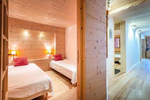 deux lits dans une chambre aux murs en bois dans l'établissement Résidence Jardins D'hiver G - JARDINS D'HIVER 10 MAE-6801, à Valmorel