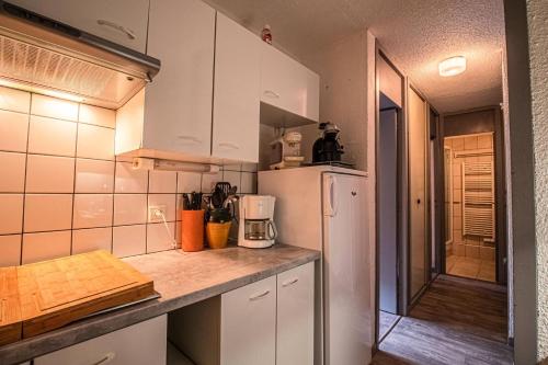 une cuisine avec des armoires blanches et un réfrigérateur blanc dans l'établissement Résidence Portail G - PORTAIL 42 MAE-7031, à Valmorel