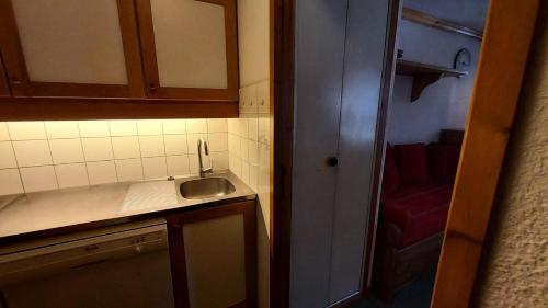 une petite cuisine avec un évier et un fauteuil rouge dans l'établissement Résidence Caillou G - CAILLOU 16 MAE-7051, à Valmorel