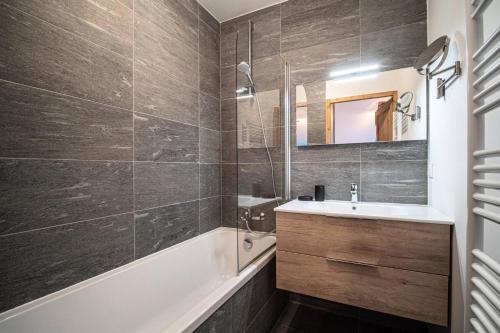 une salle de bain avec une baignoire, un lavabo et un miroir dans l'établissement Résidence Lumi Batiment B - LUMI B 504 MAE-7161, à Valmorel